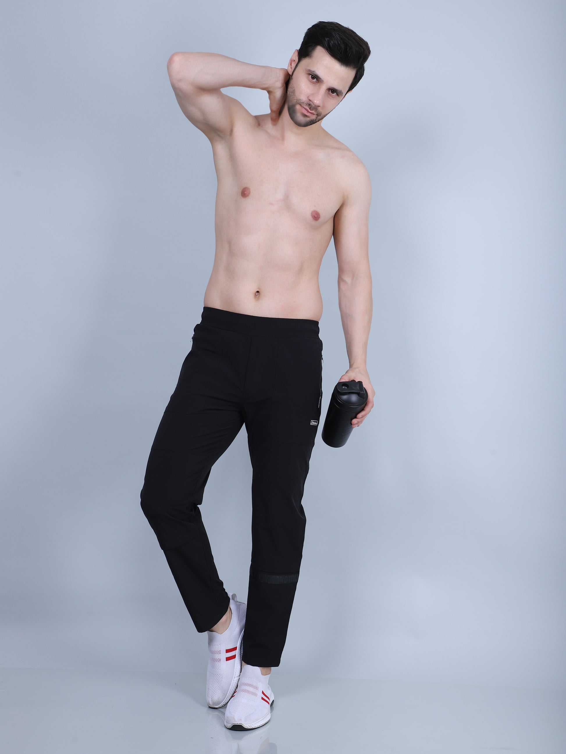 Man wearing black athletic pants and white sneakers on a light gray background