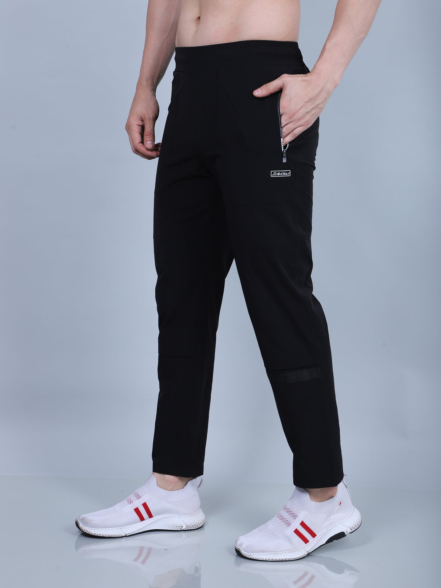 Person wearing black pants with a brand logo on a gray background