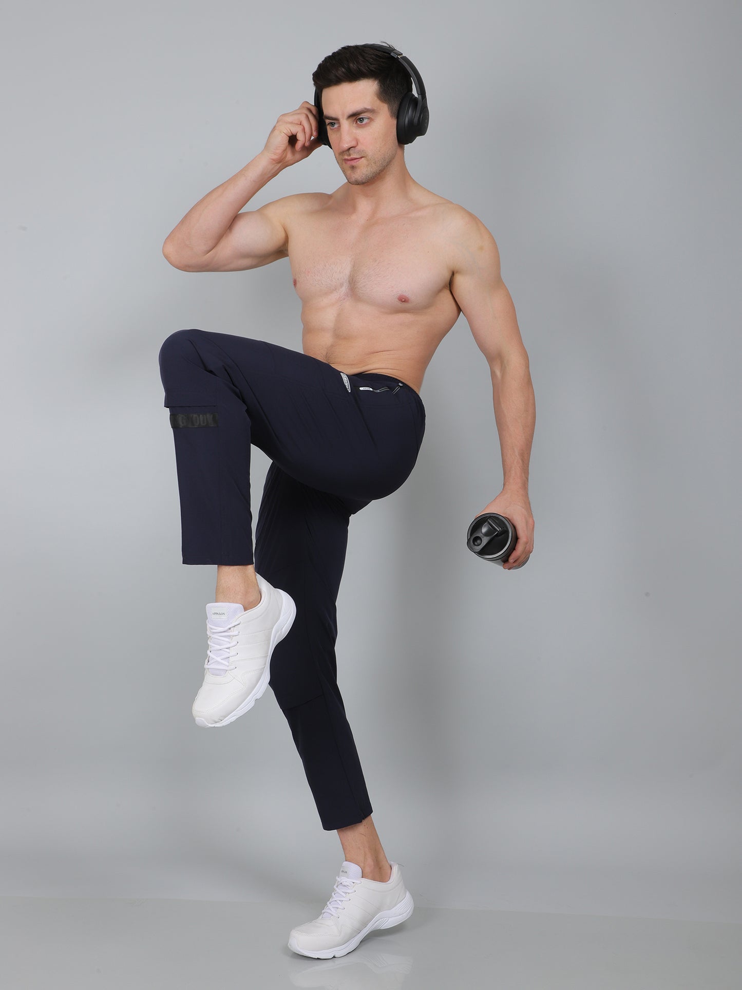 Man posing in black leggings and white sneakers on a gray background