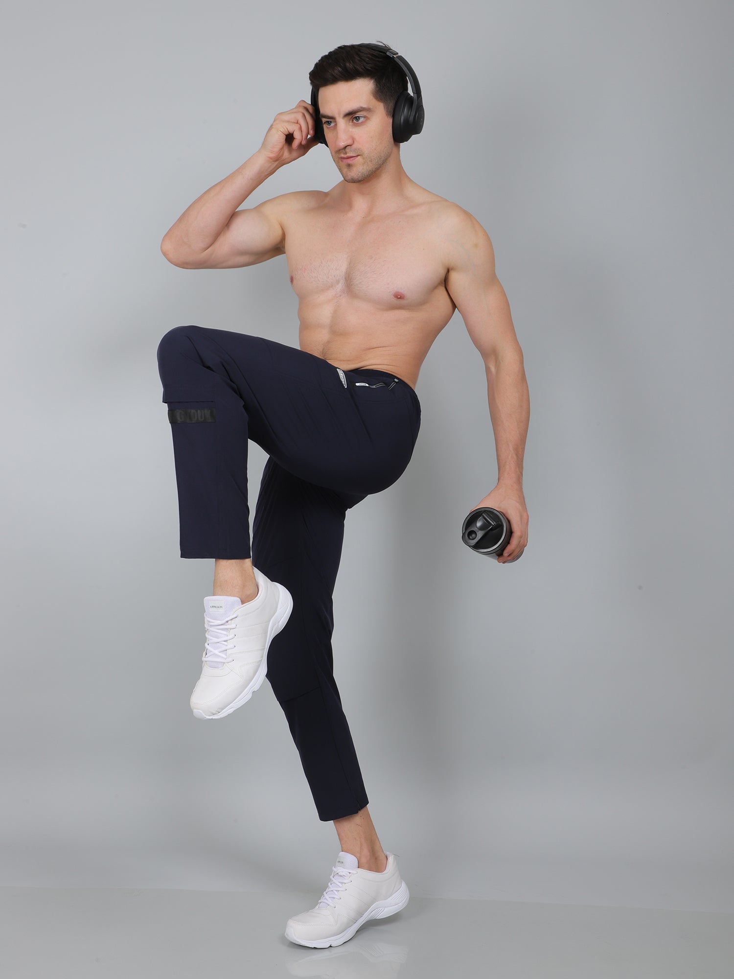 Man posing in black leggings and white sneakers on a gray background