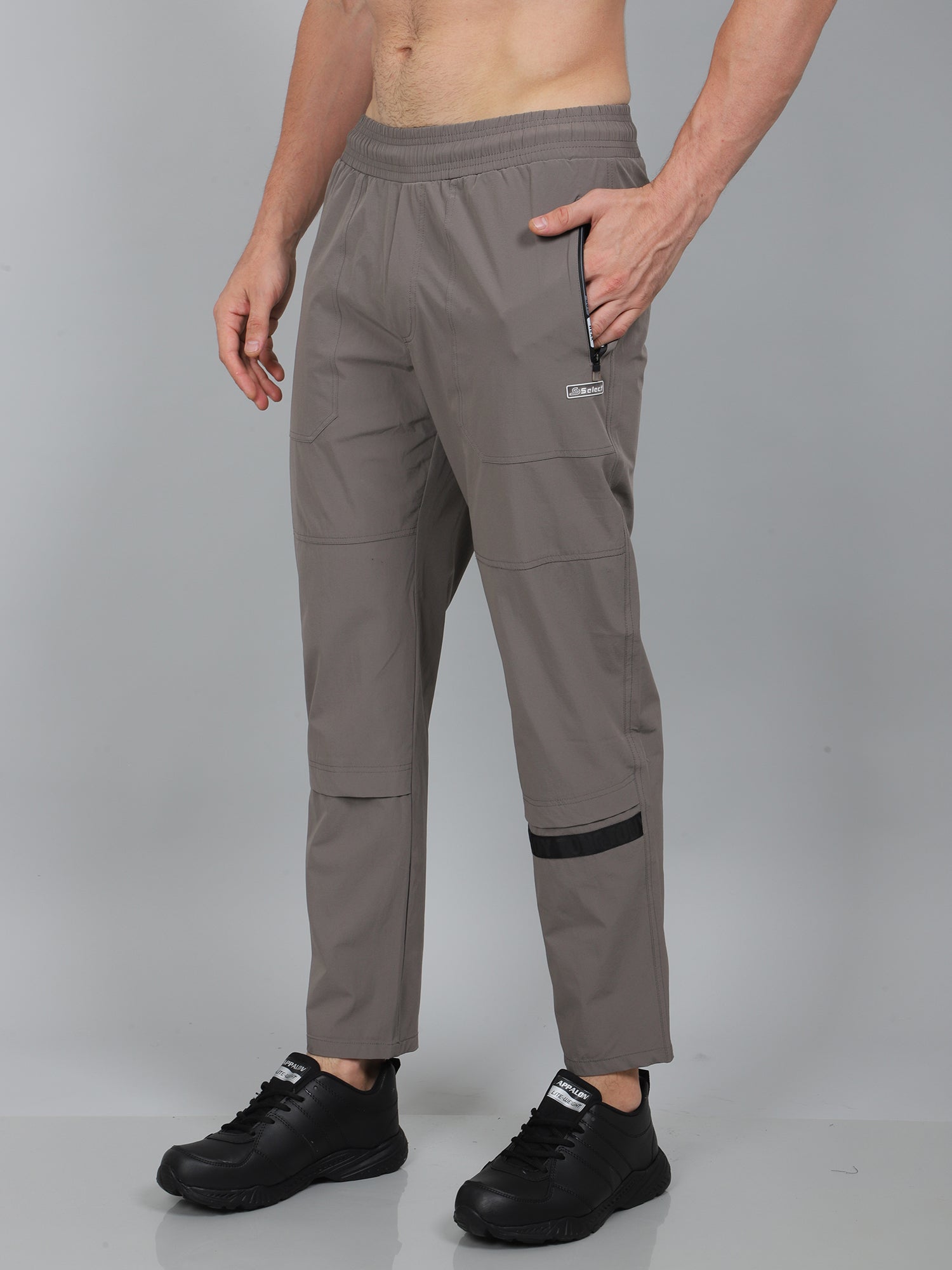 Person wearing gray pants with a visible brand logo on a gray background