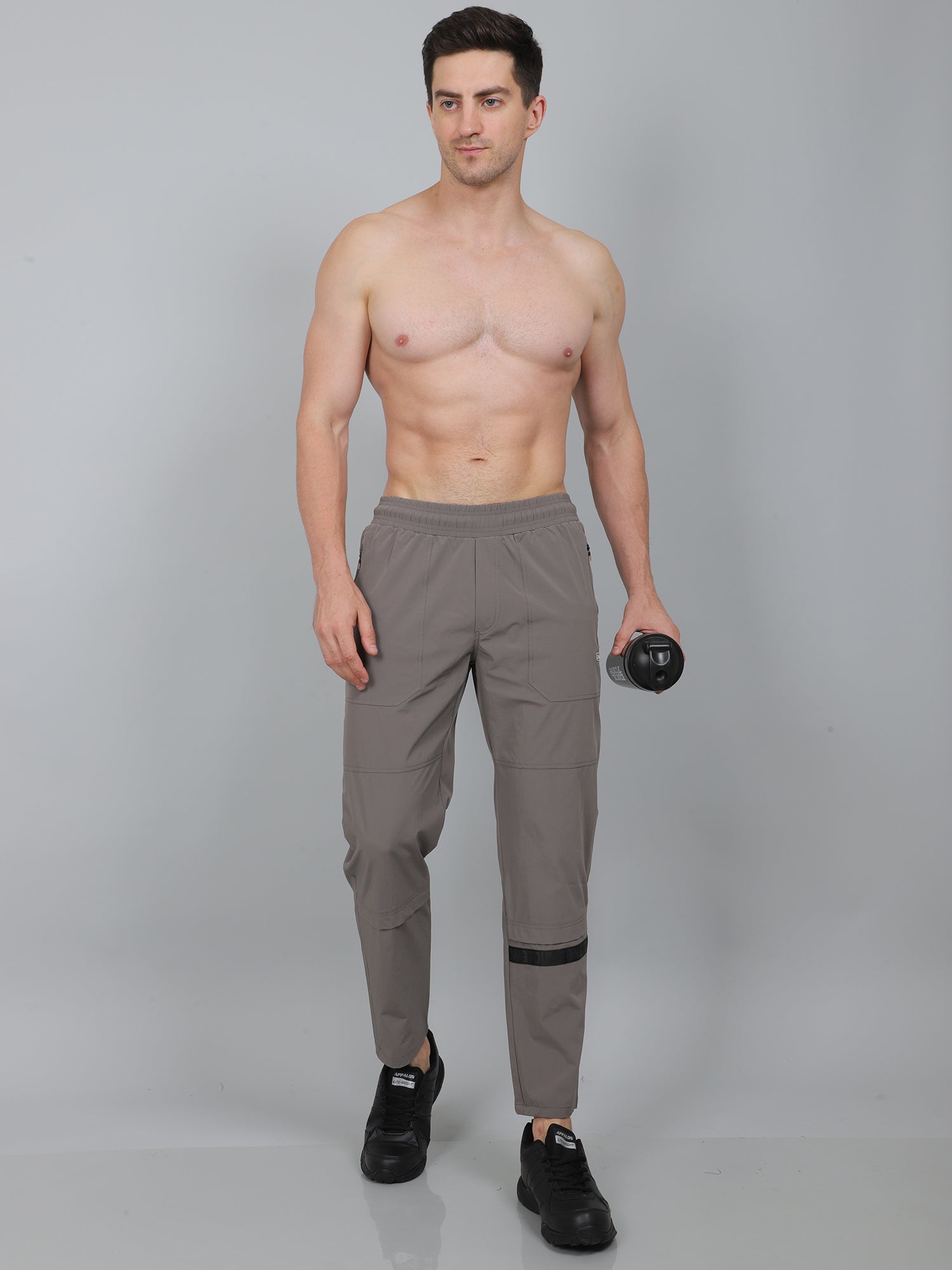 Man wearing gray pants holding a dumbbell on a gray background