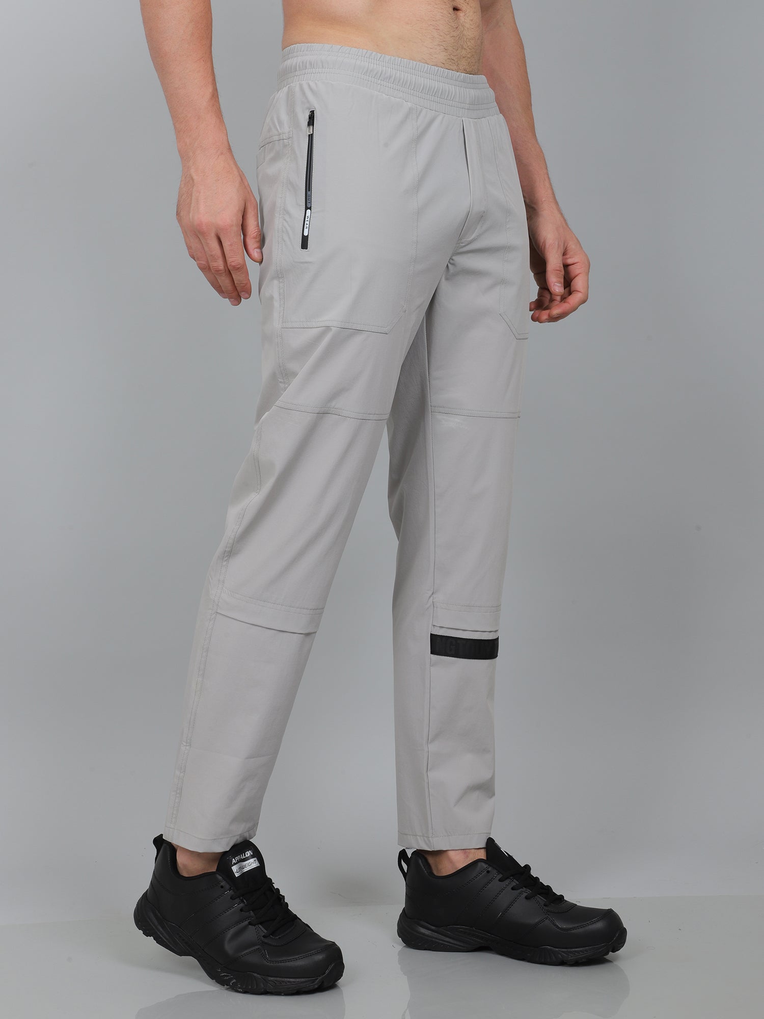 Person wearing light gray pants with black accents on a gray background