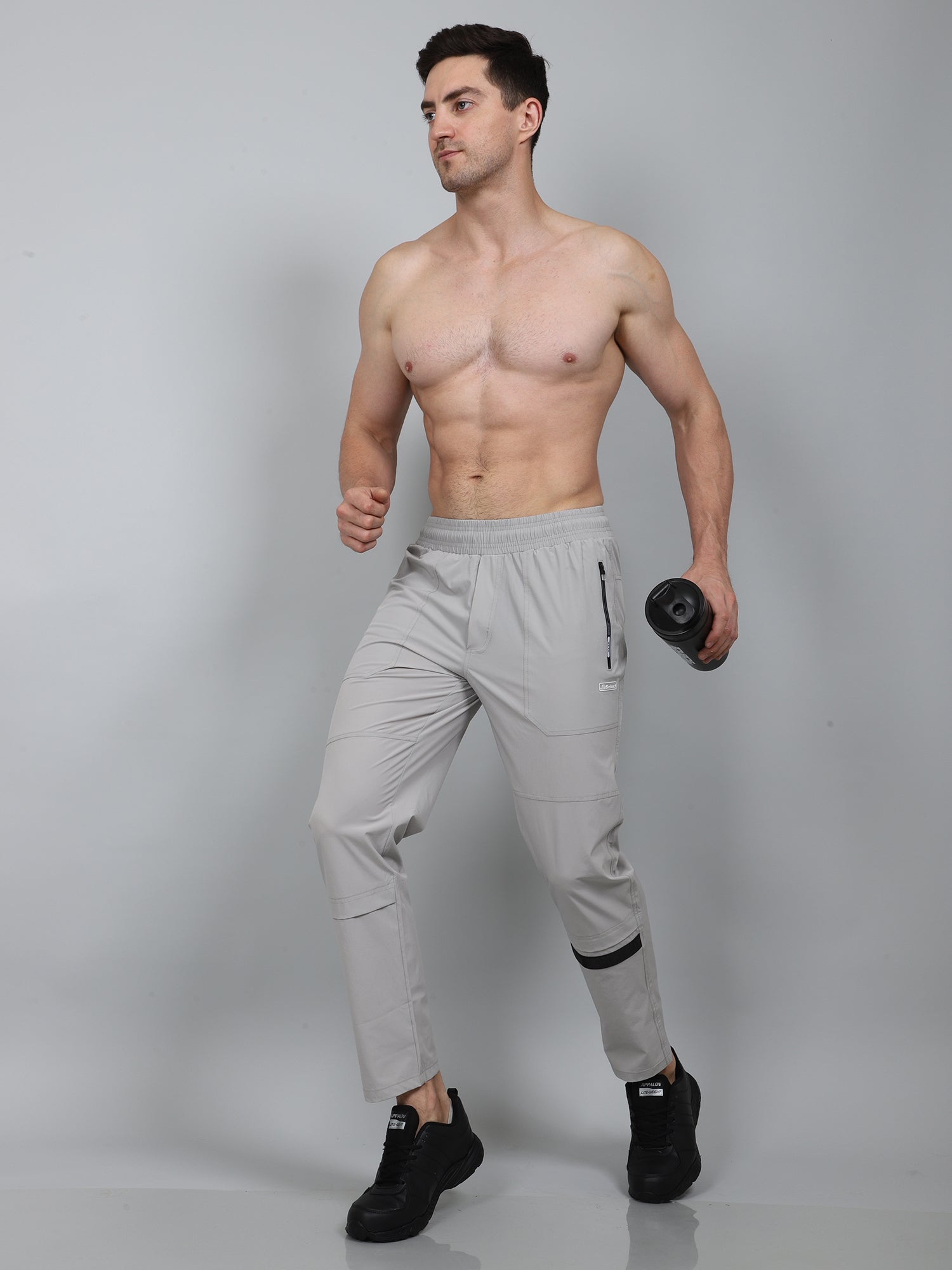 Man wearing light gray athletic pants on a plain background