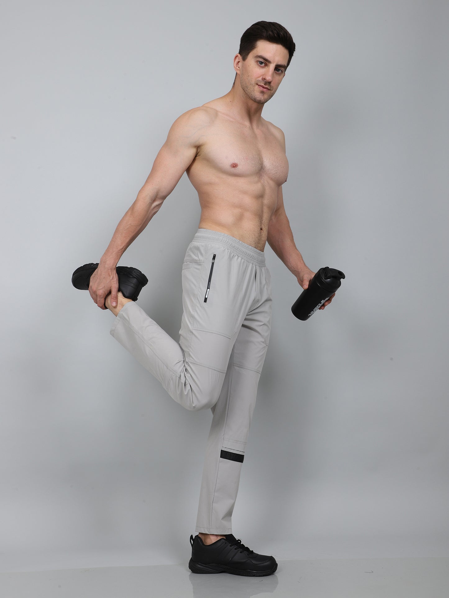 Man in light gray athletic pants posing with plain background