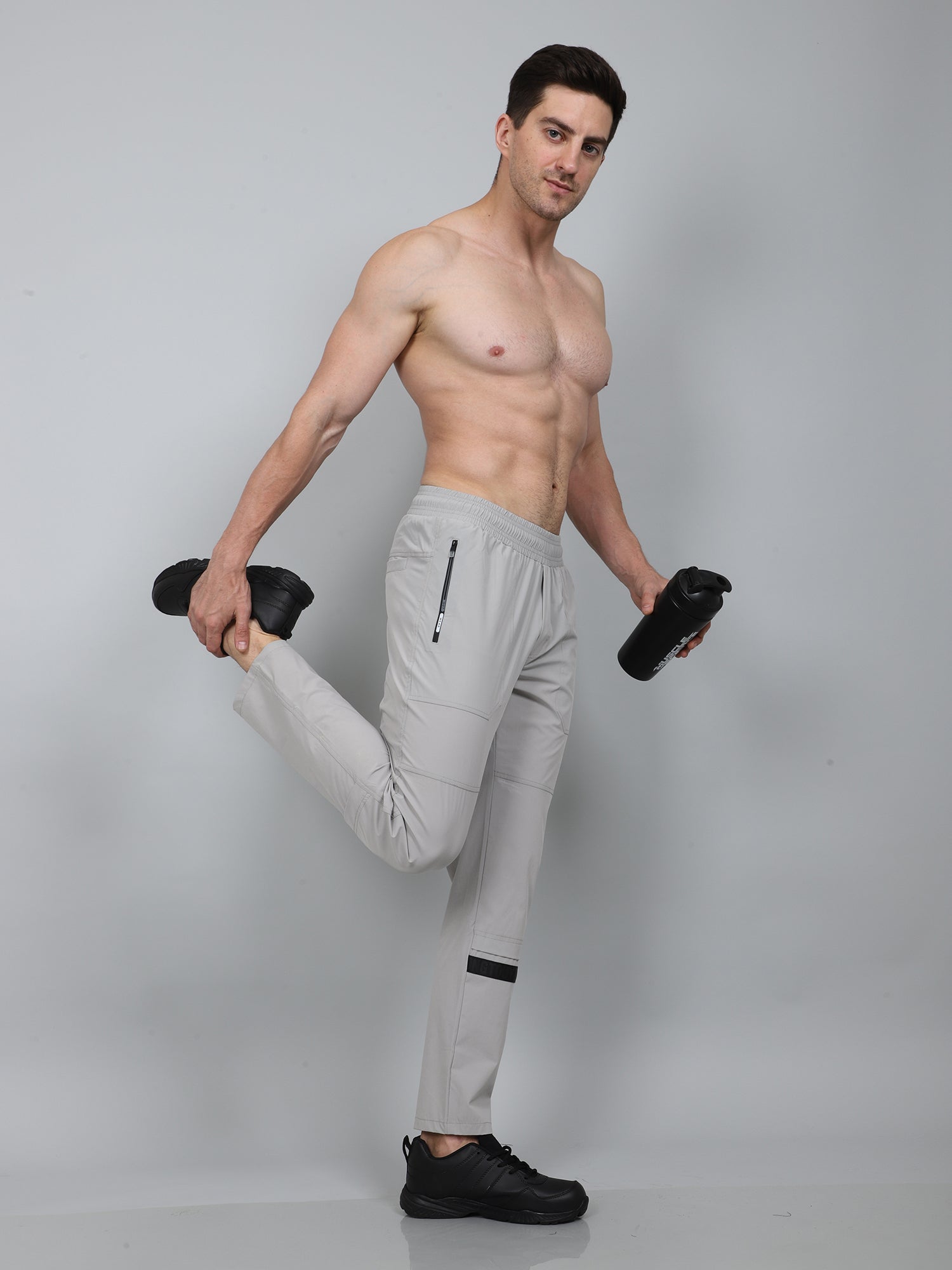 Man in light gray athletic pants posing with plain background