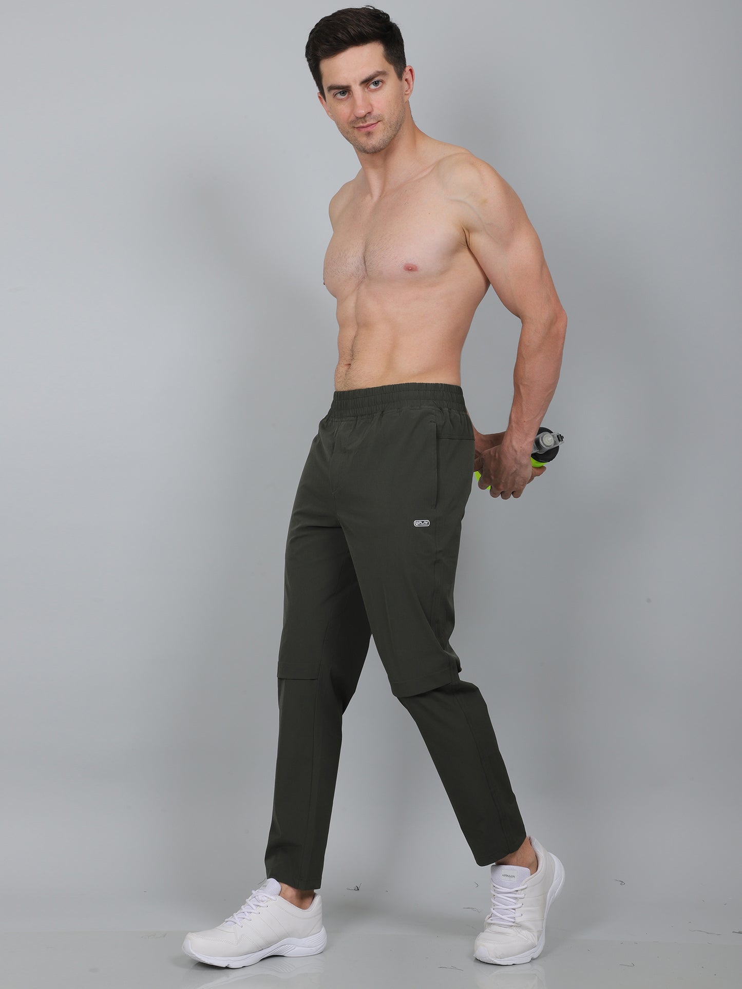 Man wearing dark green athletic pants on a gray background