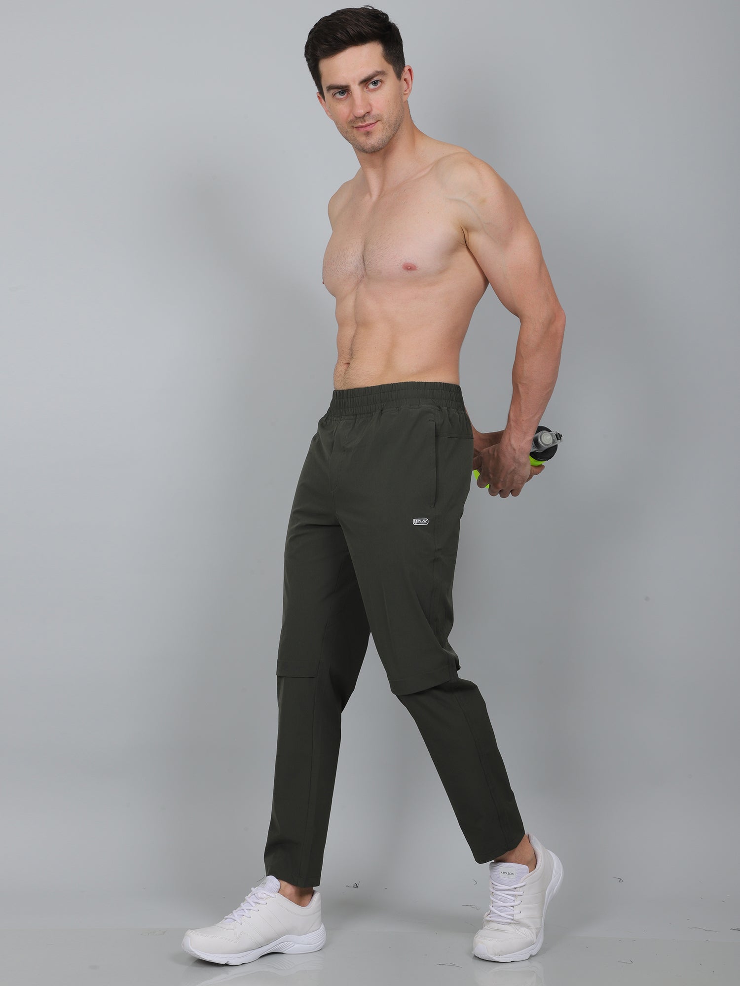 Man wearing dark green athletic pants on a gray background