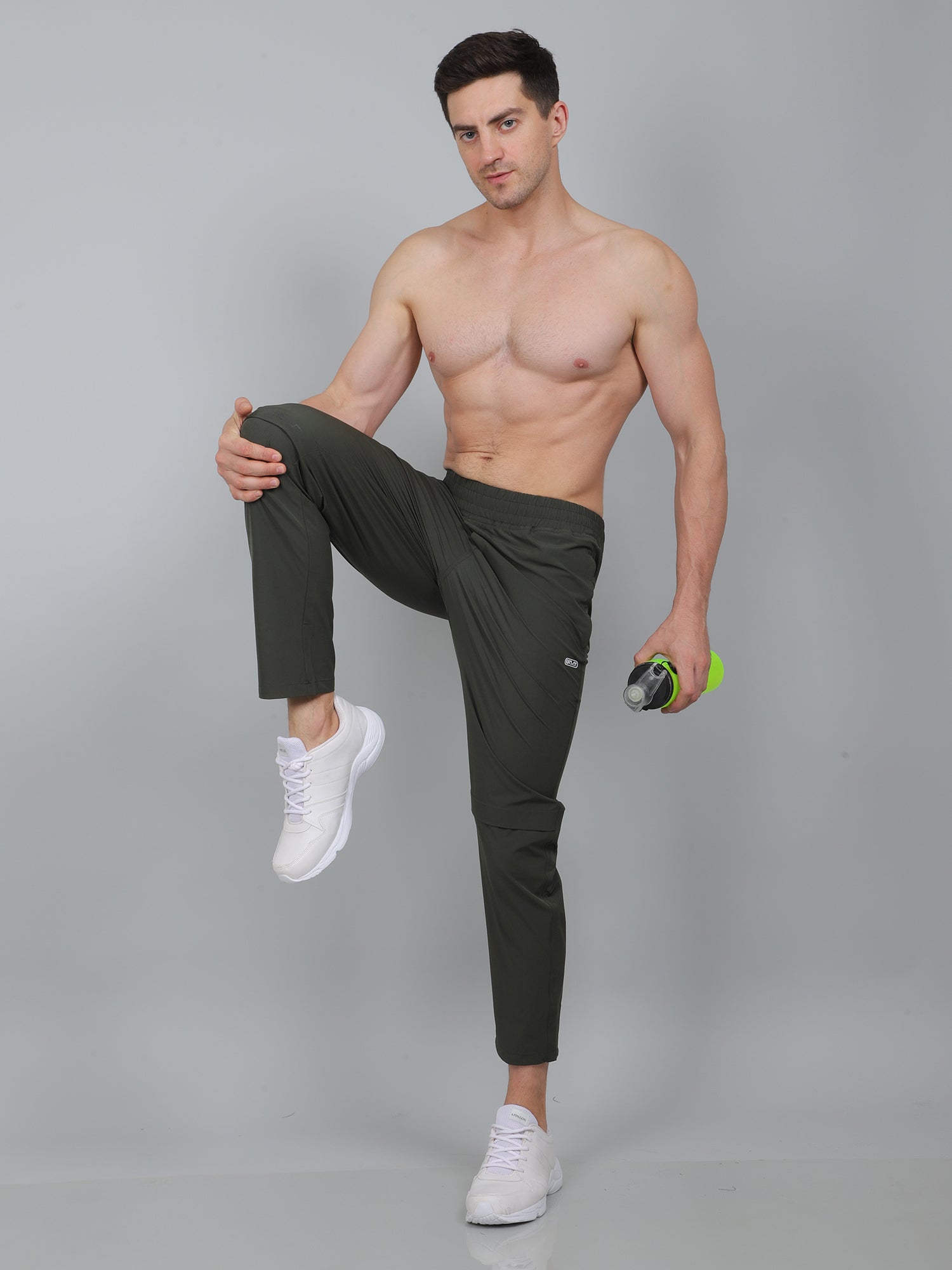 Man posing in dark pants and white sneakers on a gray background