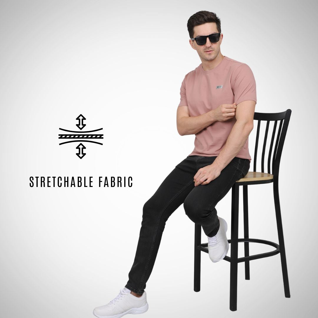 Man sitting on a chair wearing a pink shirt and black pants with 'Stretchable Fabric' text and logo.