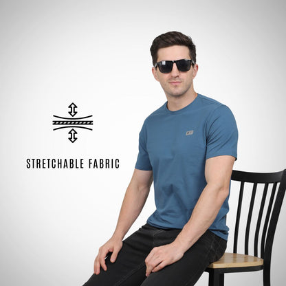 Man wearing a blue t-shirt sitting on a chair with 'Stretchable Fabric' text and logo.