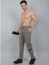 Man wearing gray pants holding a camera on a plain background
