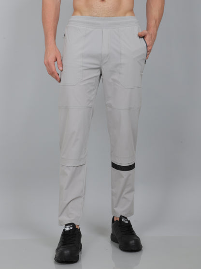 Person wearing light gray pants with black accents on a plain background